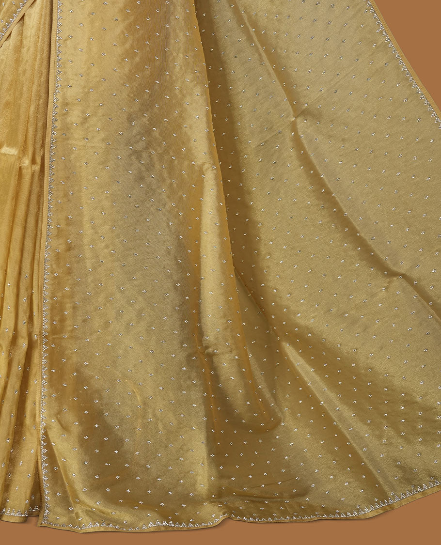 Gold colour net shimmer fancy saree adorned with scattered white stone buttas all over the body, paired with a delicate stone worked border and matching blouse.