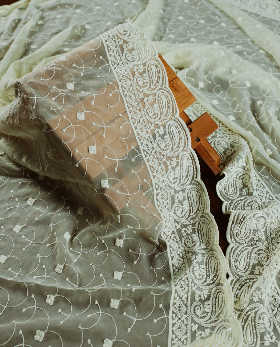 Cream and Peach churidhar material with floral thread & sequin embroidery, paired with a soft plain bottom & Comes with a sheer embroidered dupatta with fine lace borders & floral motifs for an elegant, graceful look.