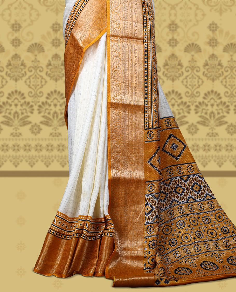 Beige Dolla silk saree featuring antique zari stripes across the body, adorned with a striking Ajrak and Traditional yellow colour border, ajrak printed pallu and paired with a perfectly matching blouse.
