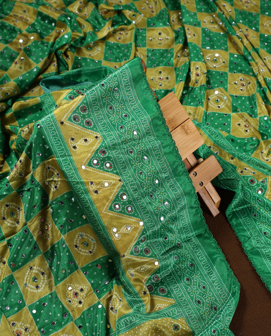 Lemon green colour churidhar material with intricate Bandhani style patterns and sparkling mirror work, Paired with a plain mustard bottom and a matching dupatta highlighted with mirror embellishments.