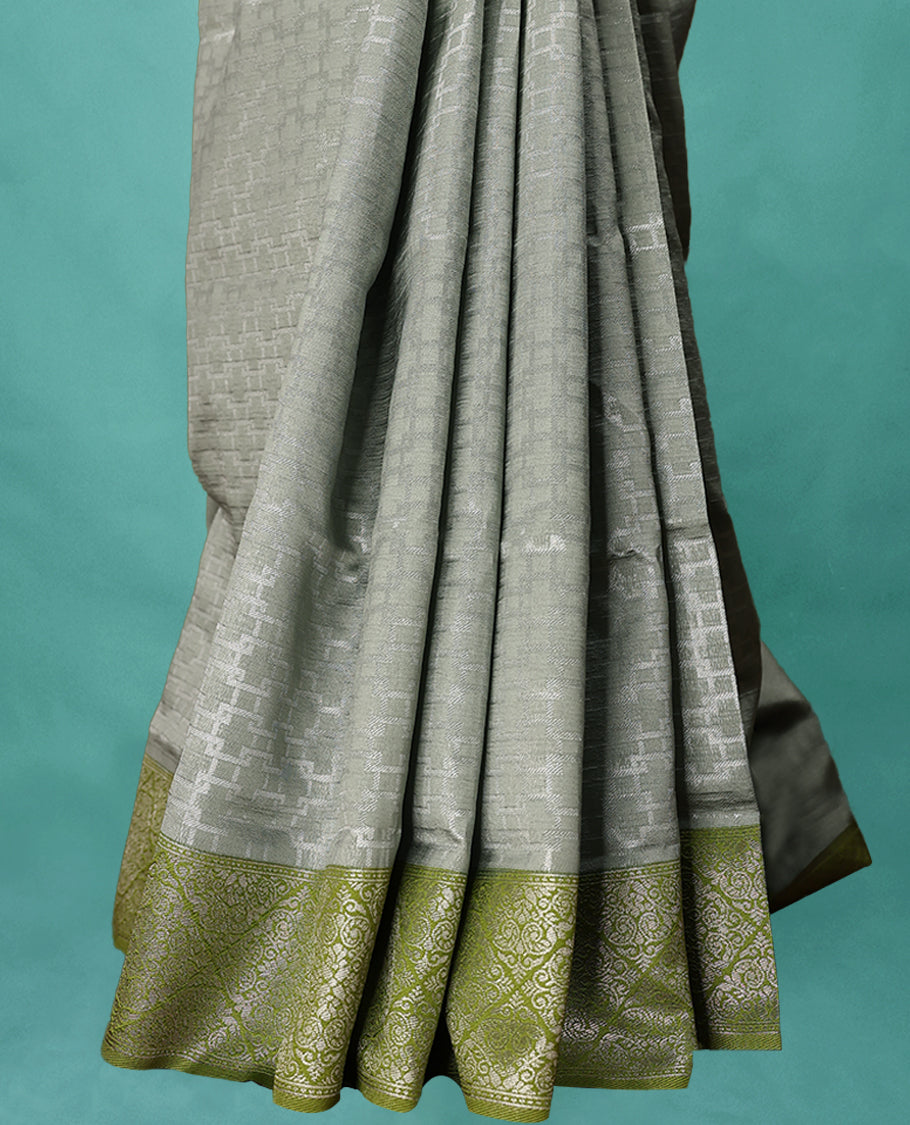 Greenish Grey coloured semi silk saree featuring a Zari design on the body, paired with a Green coloured border and matching blouse.