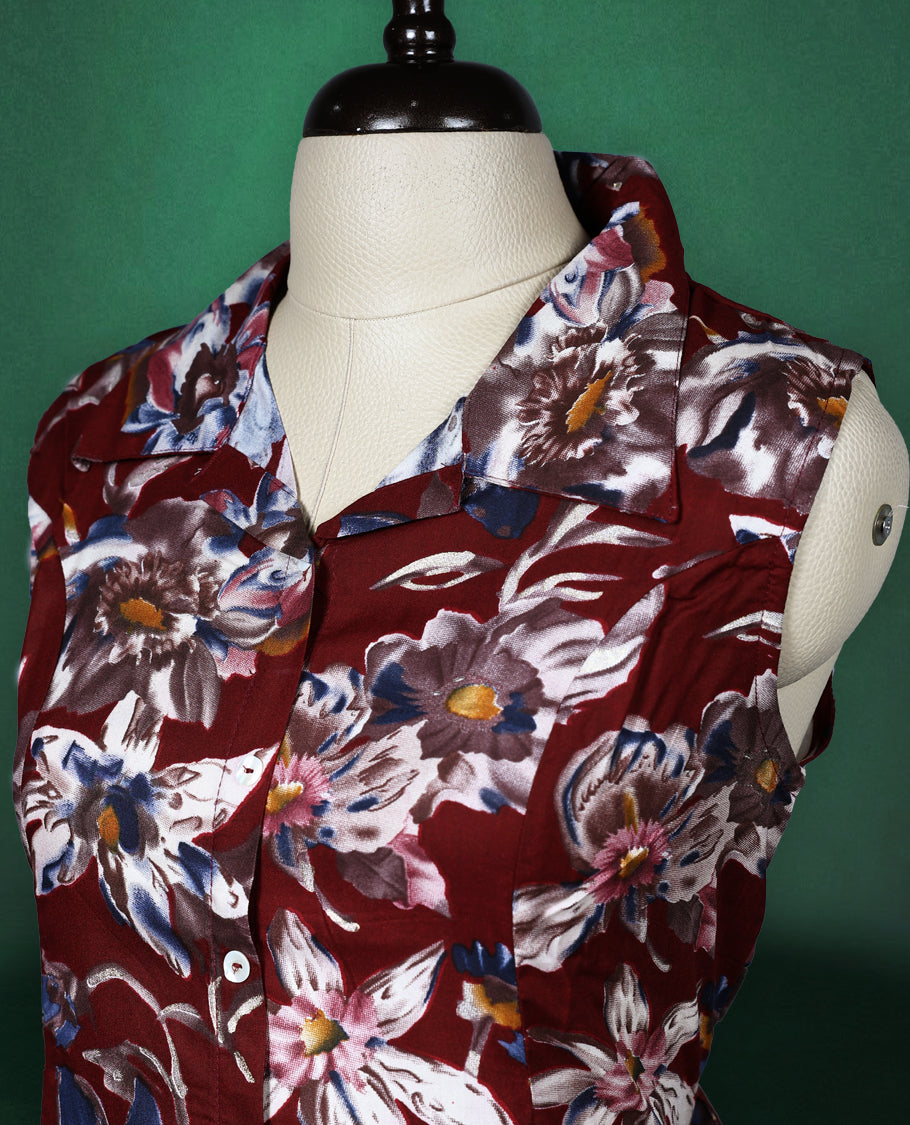 Maroon colour sleeveless dress featuring a collared neckline and button down front, adorned with bold blue and white floral prints a stylish and breathable choice for everyday elegance.
