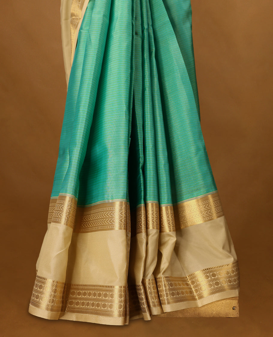 Aqua blue and green Colour soft silk saree adorned with golden zari stripes on the body, complemented by a contrasting traditional border, and paired with a matching contrast coloured blouse.