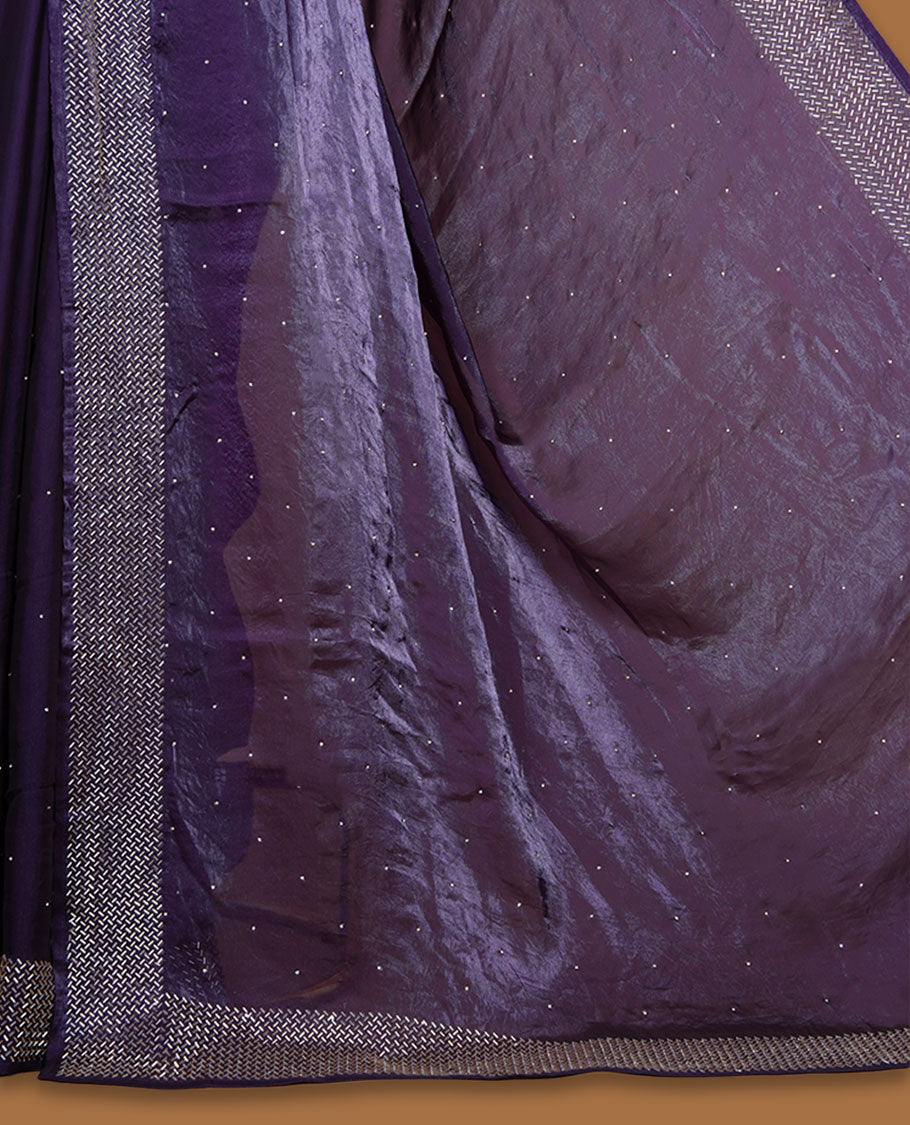 Dark purple colour chiffon designer saree, featuring dainty scattered stones on the body, enriched with dense stone work and a heavy metallic stone border and pallu, paired with a matching blouse.