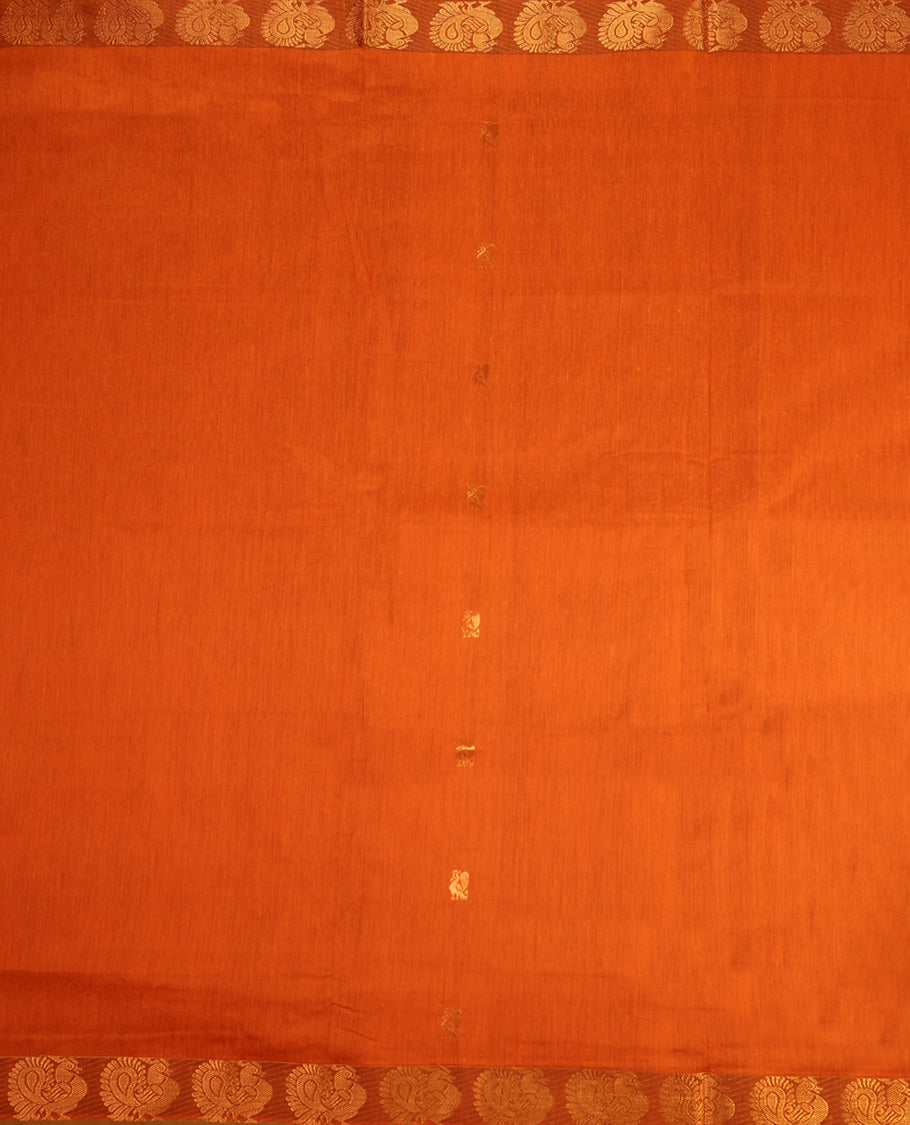 Rust Orange colour mixed Kalyani cotton saree featuring Copper zari Peacock motifs throughout the body, paired with Bottle Green colour traditional border and pallu, with matching blouse