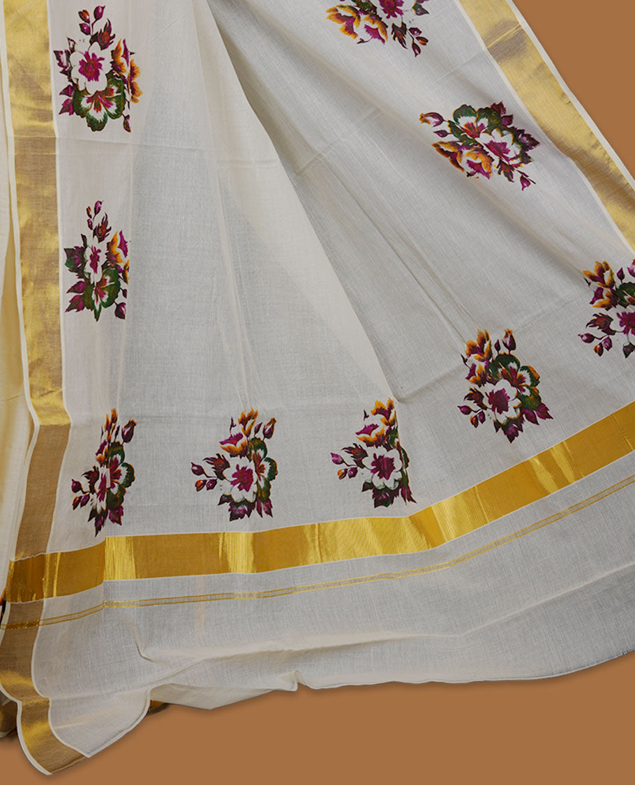 Off-white colour cotton Kerala saree with a classic gold kasavu border, adorned with multi colour floral motifs across the body and pallu, and paired with a matching blouse.