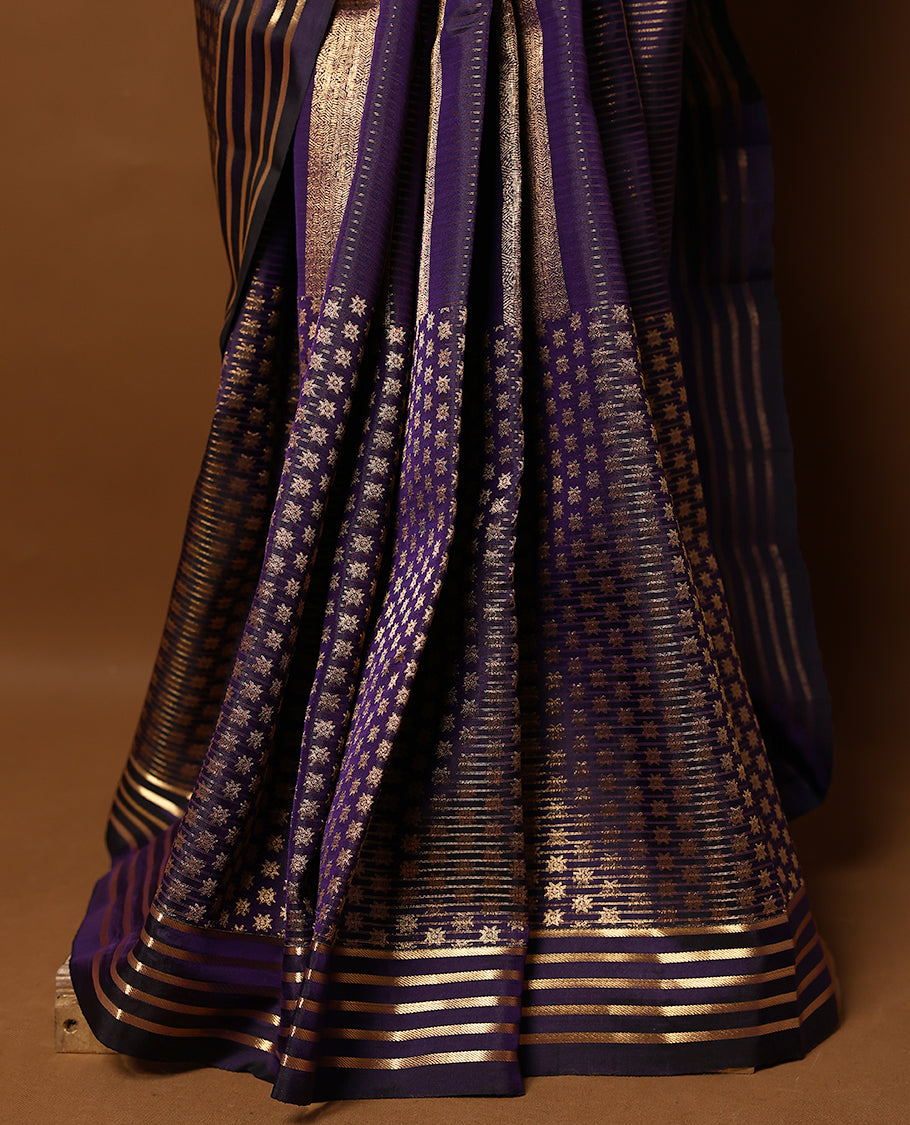 Dark purple Colour soft silk saree adorned with antique zari work, featuring a self-coloured floral border and paired with a matching blouse.