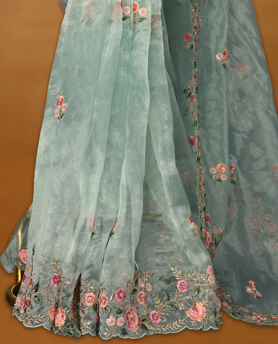 Pastel Aqua Organza Tissue Silk Saree is beautifully adorned with intricate pink floral embroidery Border and a matching blouse.