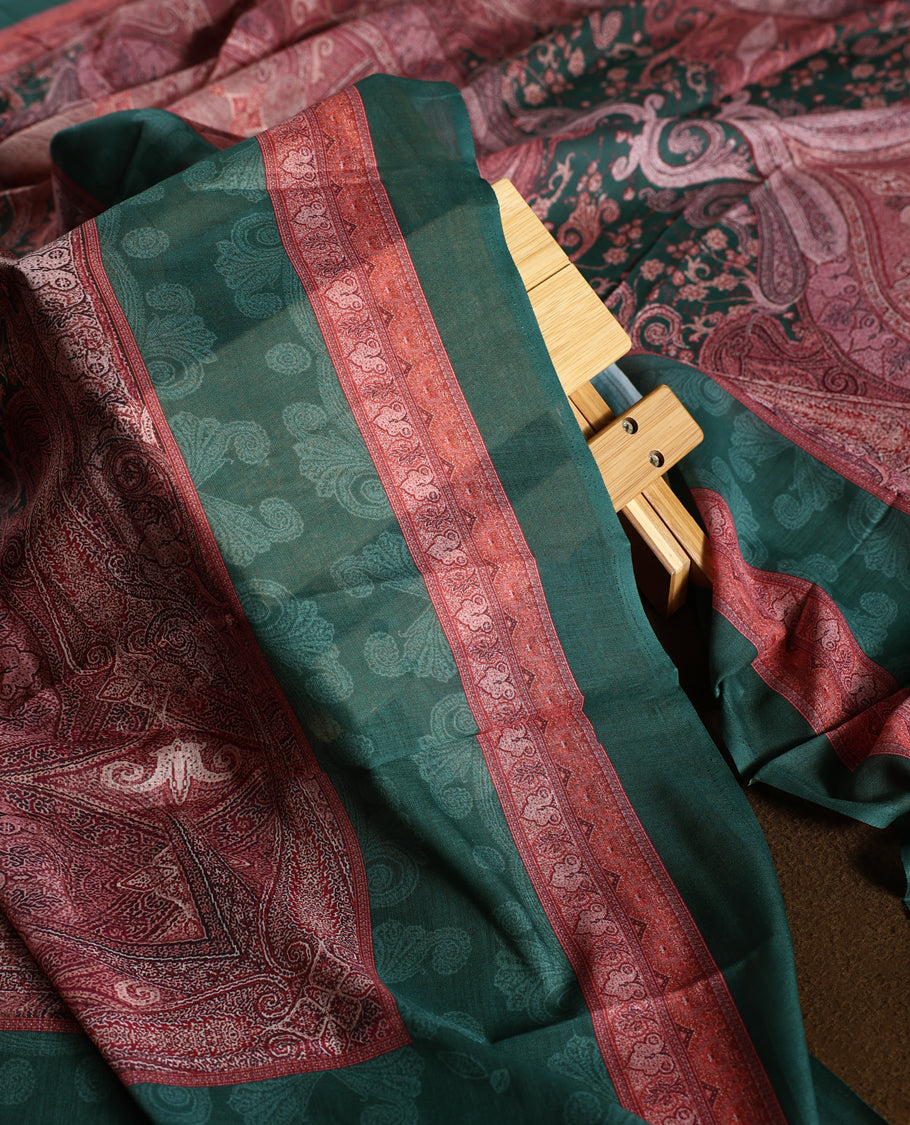 Dark green colour churidhar material featuring intricate embroidery with subtle paisley patterns, paired with a richly printed dupatta and plain bottom.