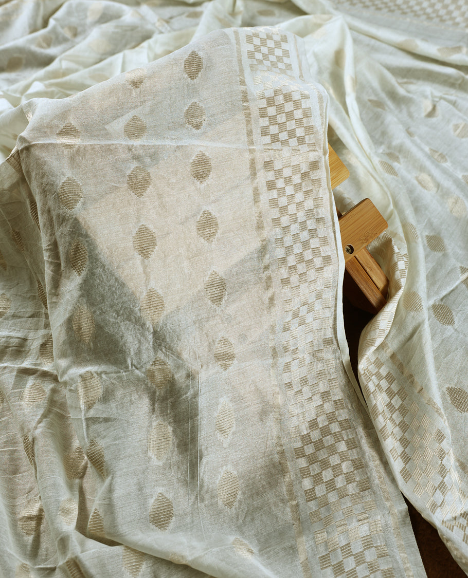 Off white colour churidhar material featuring delicate thread embroidery with paisley and floral motifs, paired with a plain bottom & Comes with a soft dupatta woven with subtle golden zari patterns.