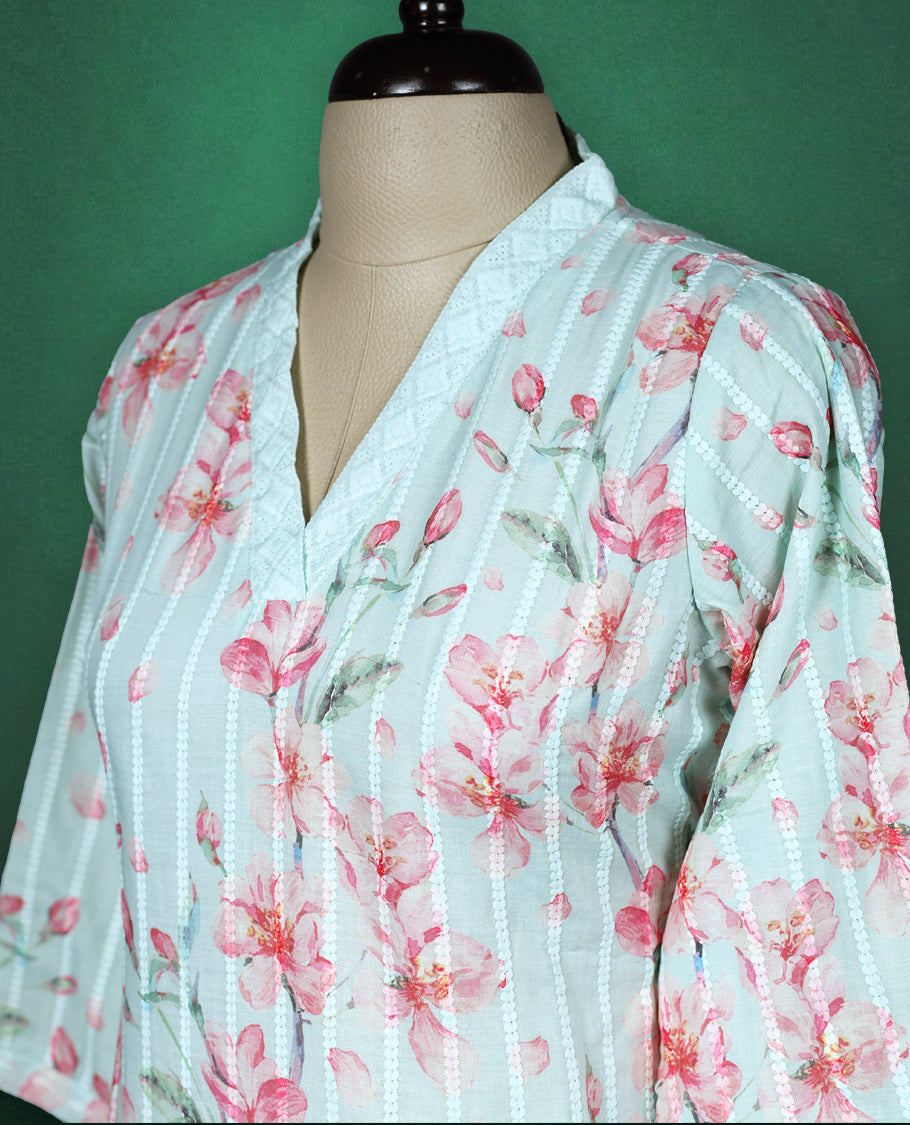 Mint green cotton kurti adorned with pink floral prints and white vertical stripes, featuring a V slit collared neckline, three quarter sleeves, and a white lace trimmed hem, fresh and feminine pick for everyday comfort.