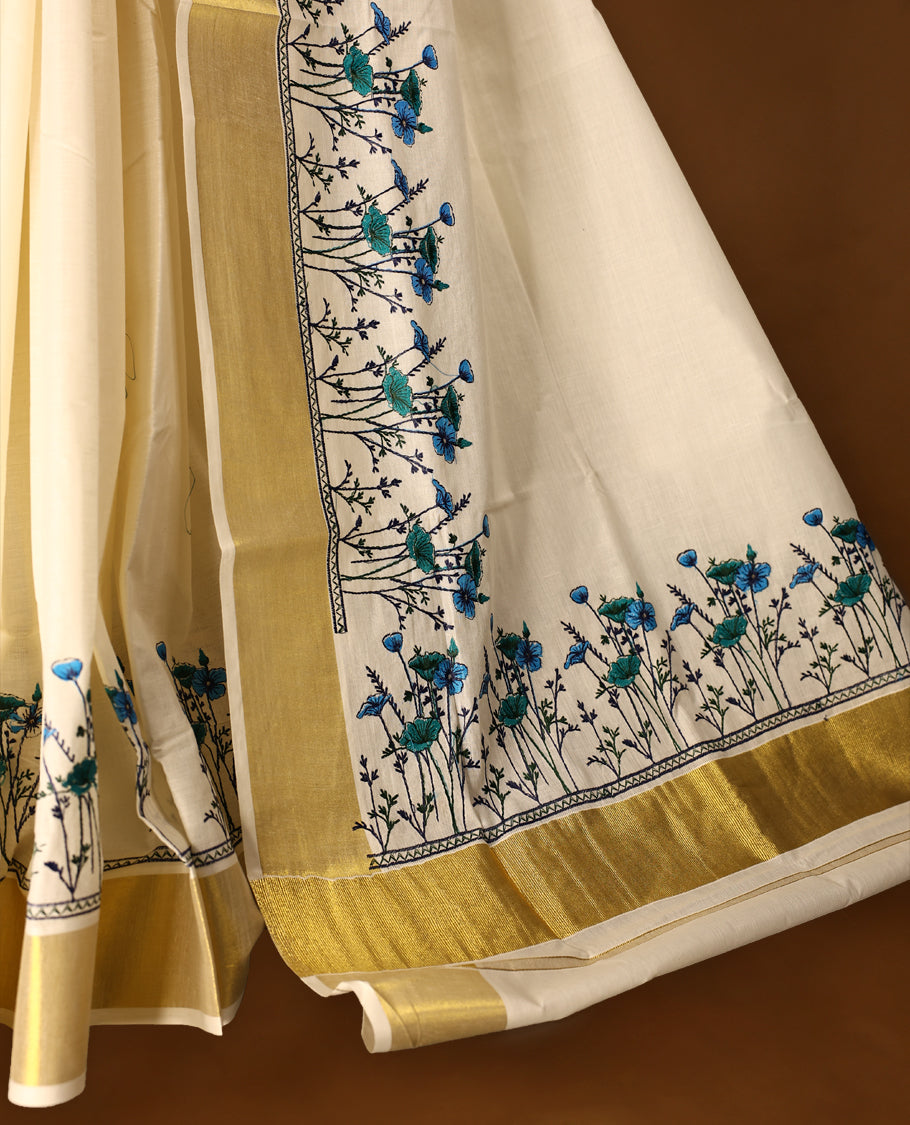 Light Gold colour Cotton Kerala saree featuring Plain body and a beautifully woven Gold Kasavu border with Heavy Blue and Green colour Floral embroidery work, paired with a matching blouse perfect for festive occasions.