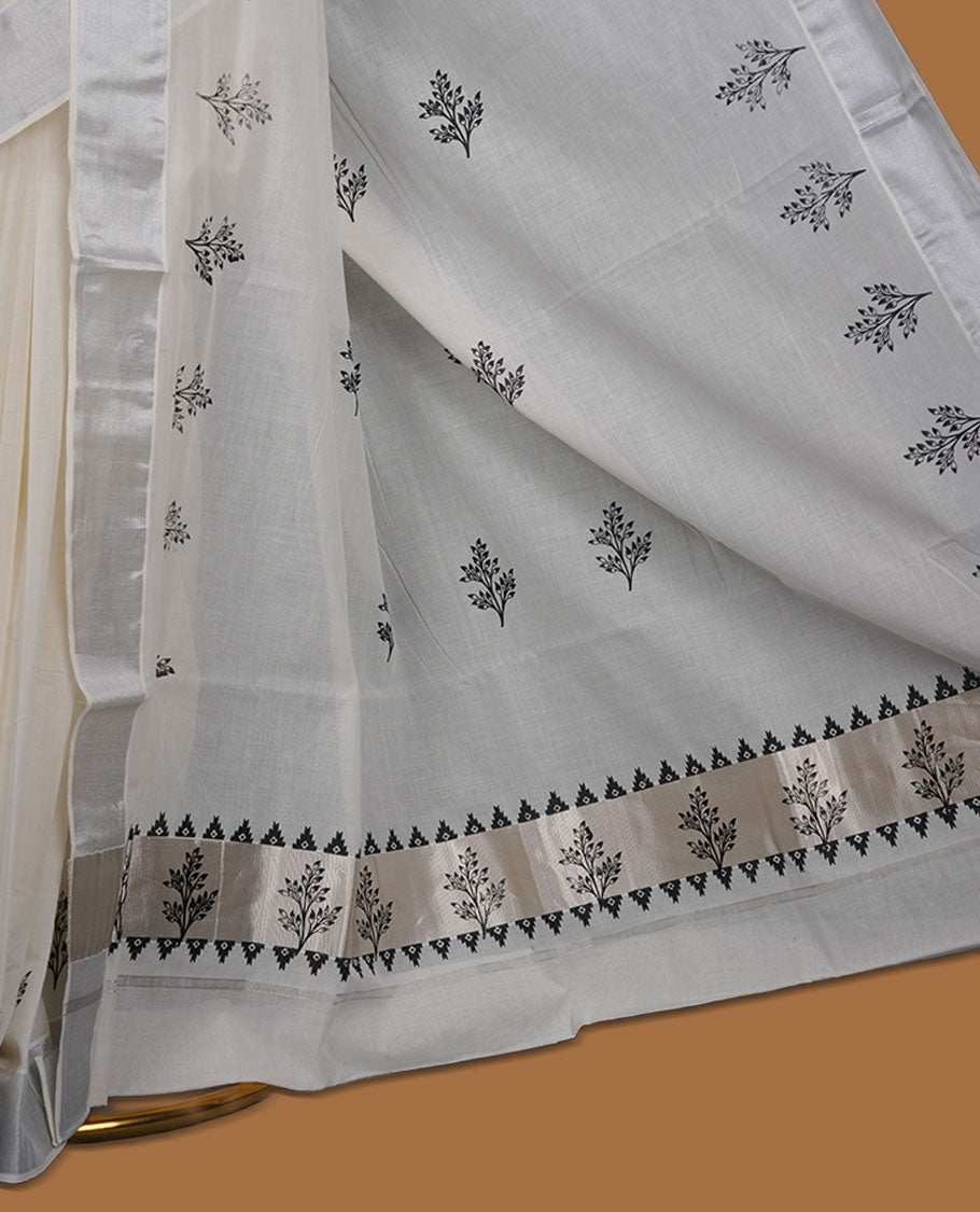 Off-white colour cotton Kerala saree featuring a subtle silver-toned border, adorned with delicate black leafy motifs across the body and pallu, and paired with a matching blouse.