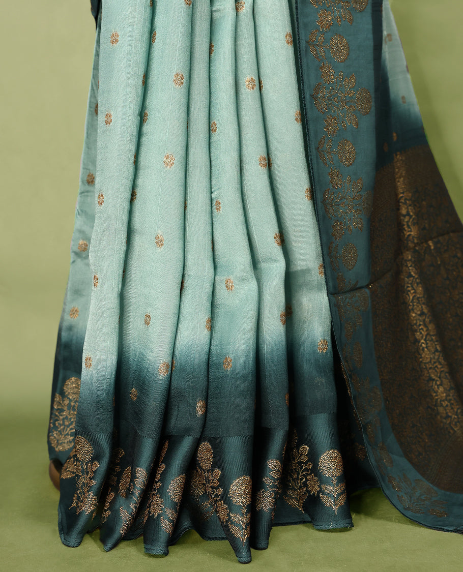 Sea green and teal double shade semi Banaras Tussar Georgette saree adorned with elegant antique gold zari floral motifs across the body, featuring a detailed woven border and grand pallu, paired with a matching blouse piece.
