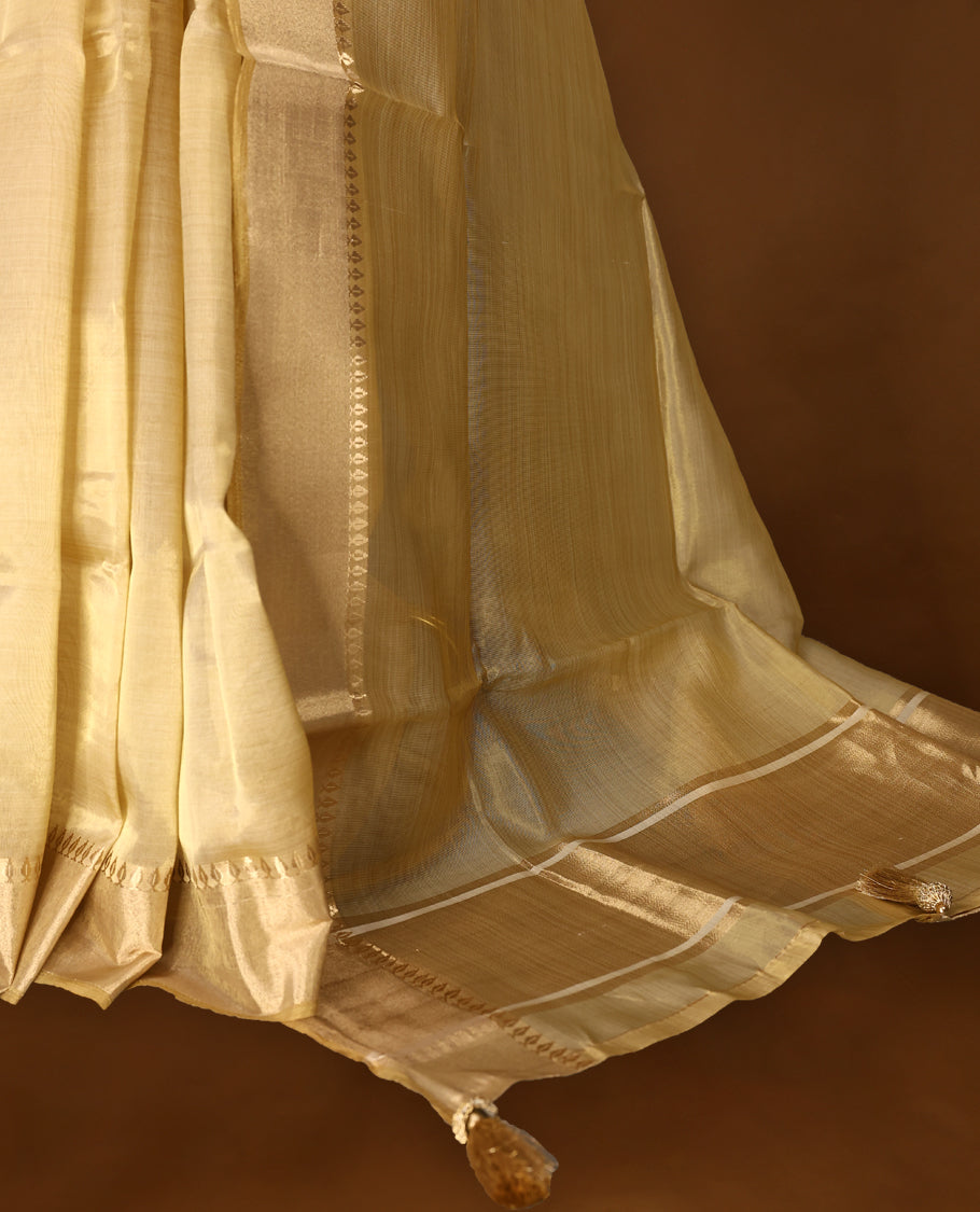 Light gold colour Organza Kerala saree featuring a sheer, luminous body with a soft golden stripes, highlighted by a sleek zari border, Minimal and elegant, it is paired gracefully with a matching blouse piece.
