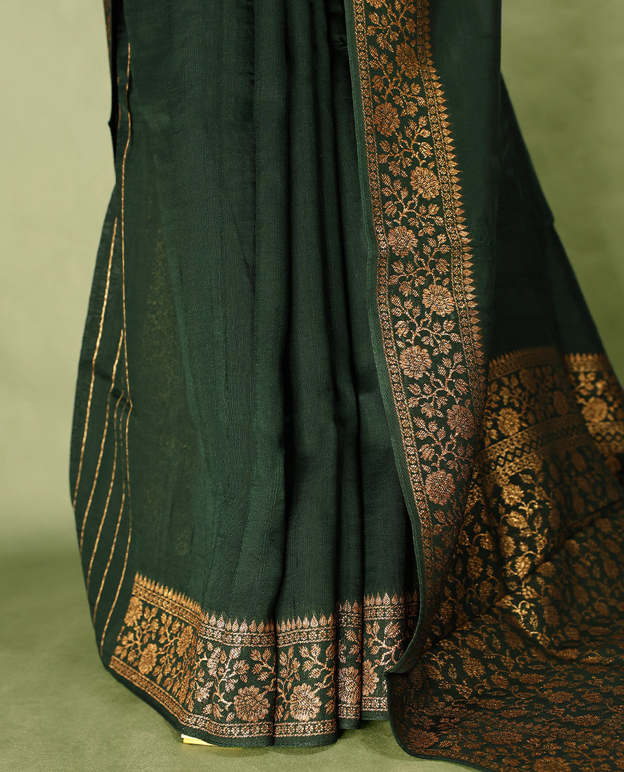 Bottle Green colour Tussar Banaras saree featuring a plain body, rich floral woven zari border and grand pallu, paired with a matching blouse for an elegant and regal traditional look.