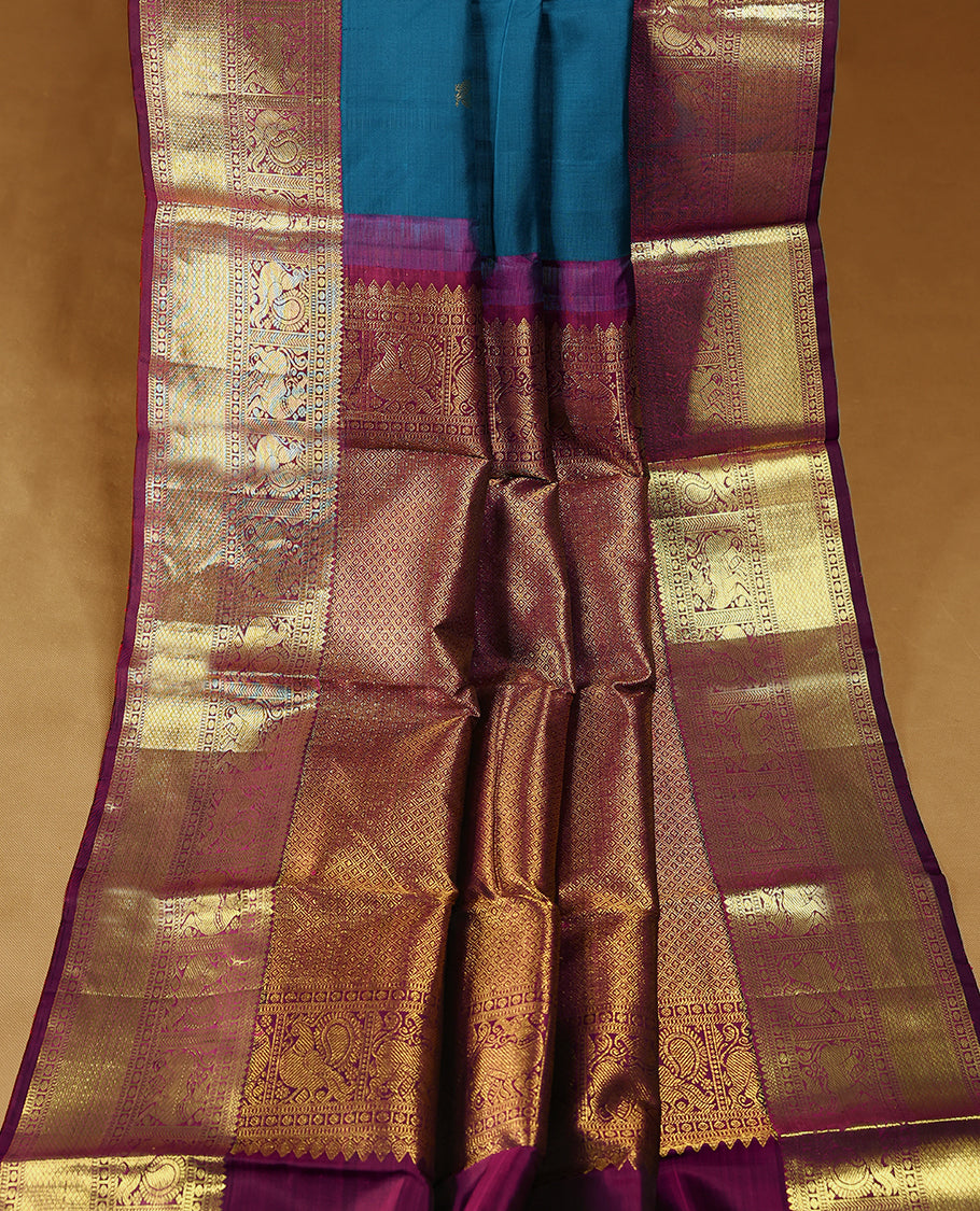 Blue Colour pure traditional Kancheepuram silk saree featuring antique zari peacock and chakkram motifs on the body, complemented by a traditional contrast coloured border and a matching contrast blouse.
