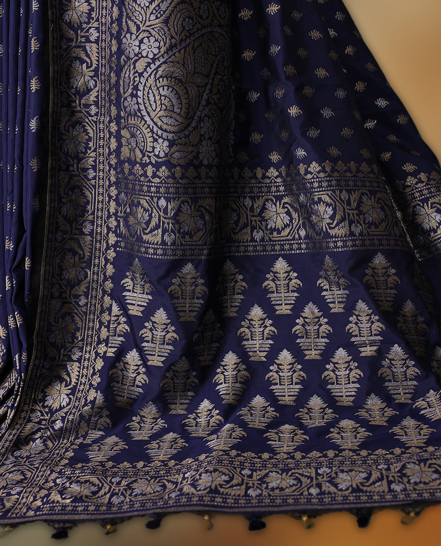 Graceful navy blue Banaras soft silk saree with gold zari buttas on the body, intricate floral zari border, grand pallu with paisley motifs, and a matching blouse. Perfect for weddings and celebrations.