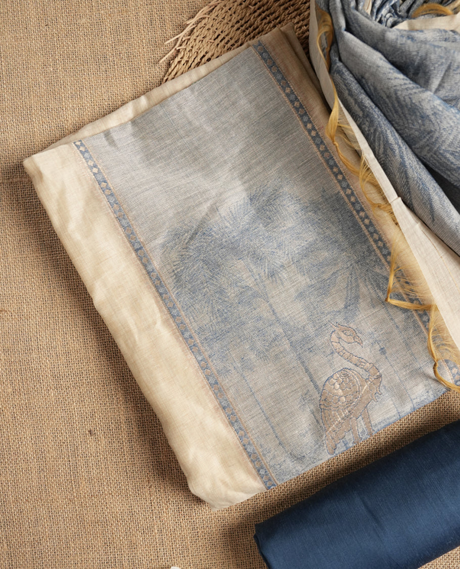 Beige & Blue colour suit material adorned with intricate woven patterns, bird print & subtle motifs, exuding ethnic grace & paired with a beautifully bordered dupatta and a matching plain bottom.