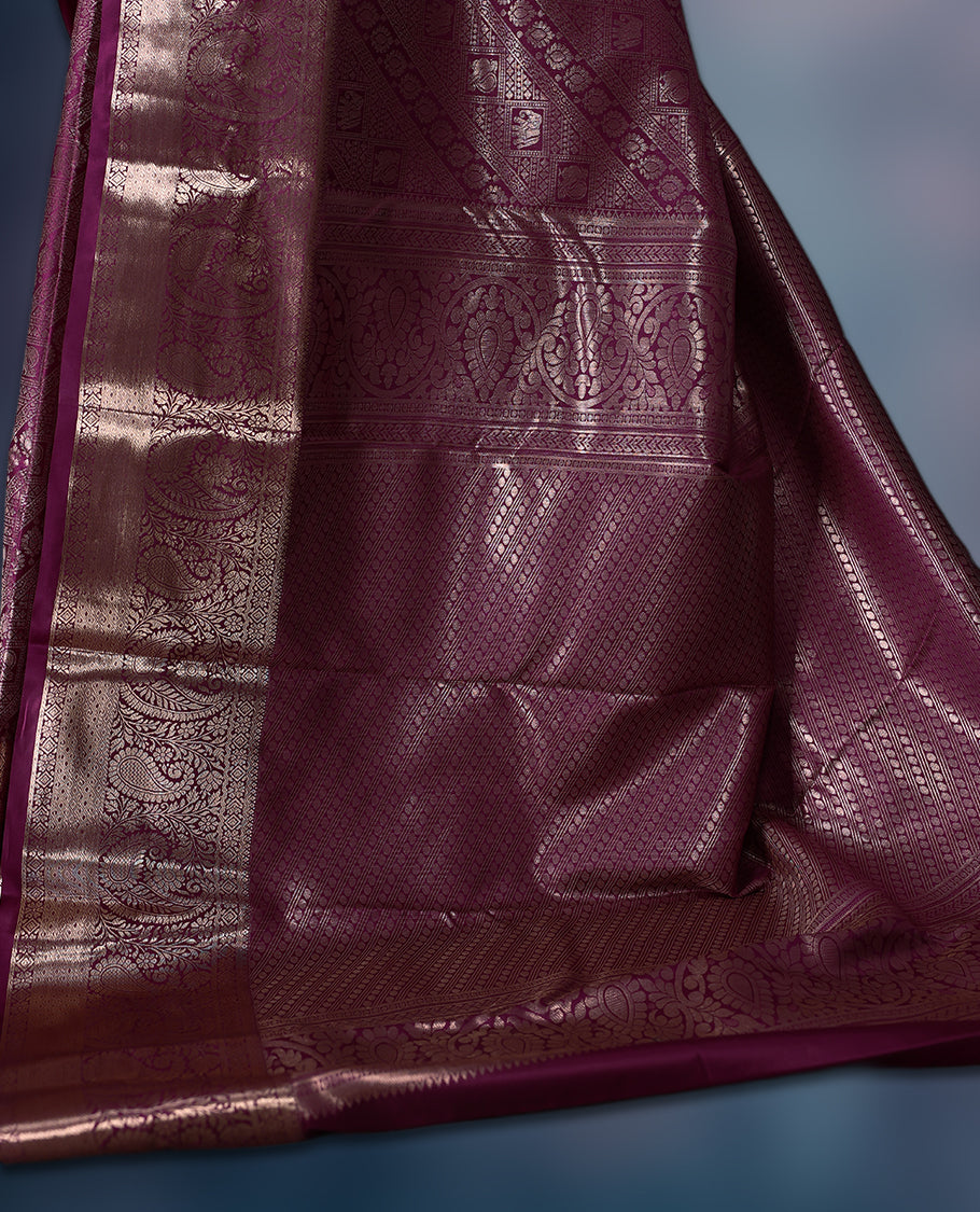 Grape colour semi silk brocade saree featuring intricate golden zari floral and geometric patterns all over the body, complemented by a rich self-colour woven border and pallu, paired with a matching blouse.