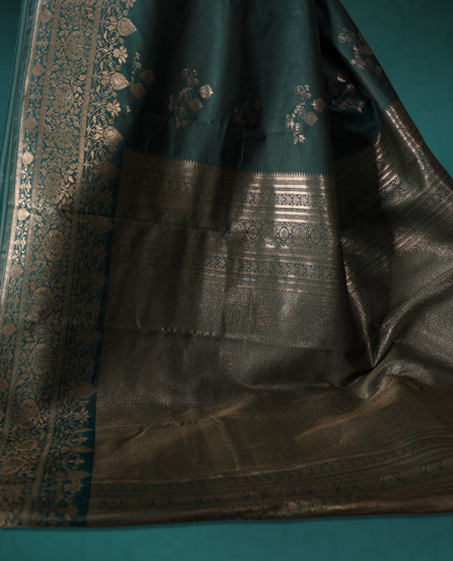 Teal green colour semi silk saree featuring elegant silver zari floral motifs across the body, complemented by a rich self-colour woven border and pallu, paired with a matching blouse.