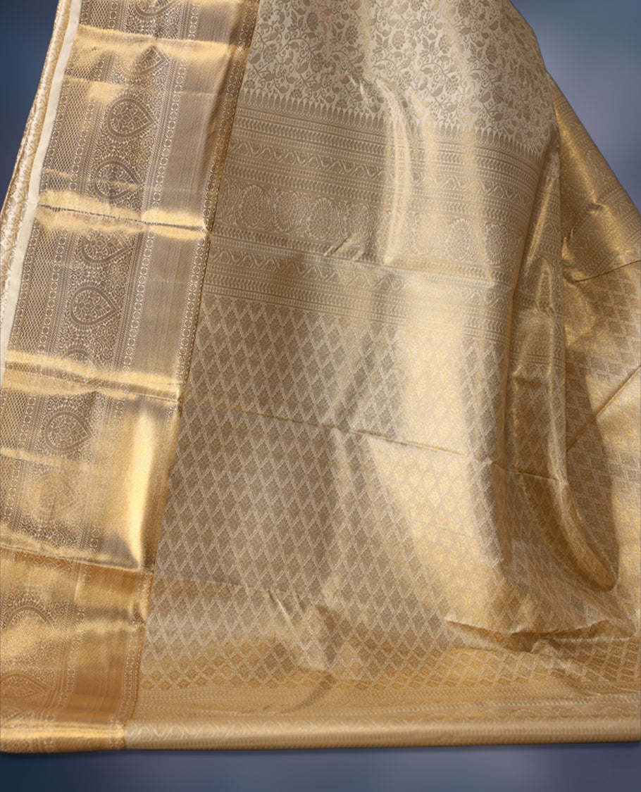 Ivory gold semi silk brocade saree with rich self brocade detailing across the body, paired with an opulent gold woven border and pallu. Comes with a matching blouse for a timeless traditional look.