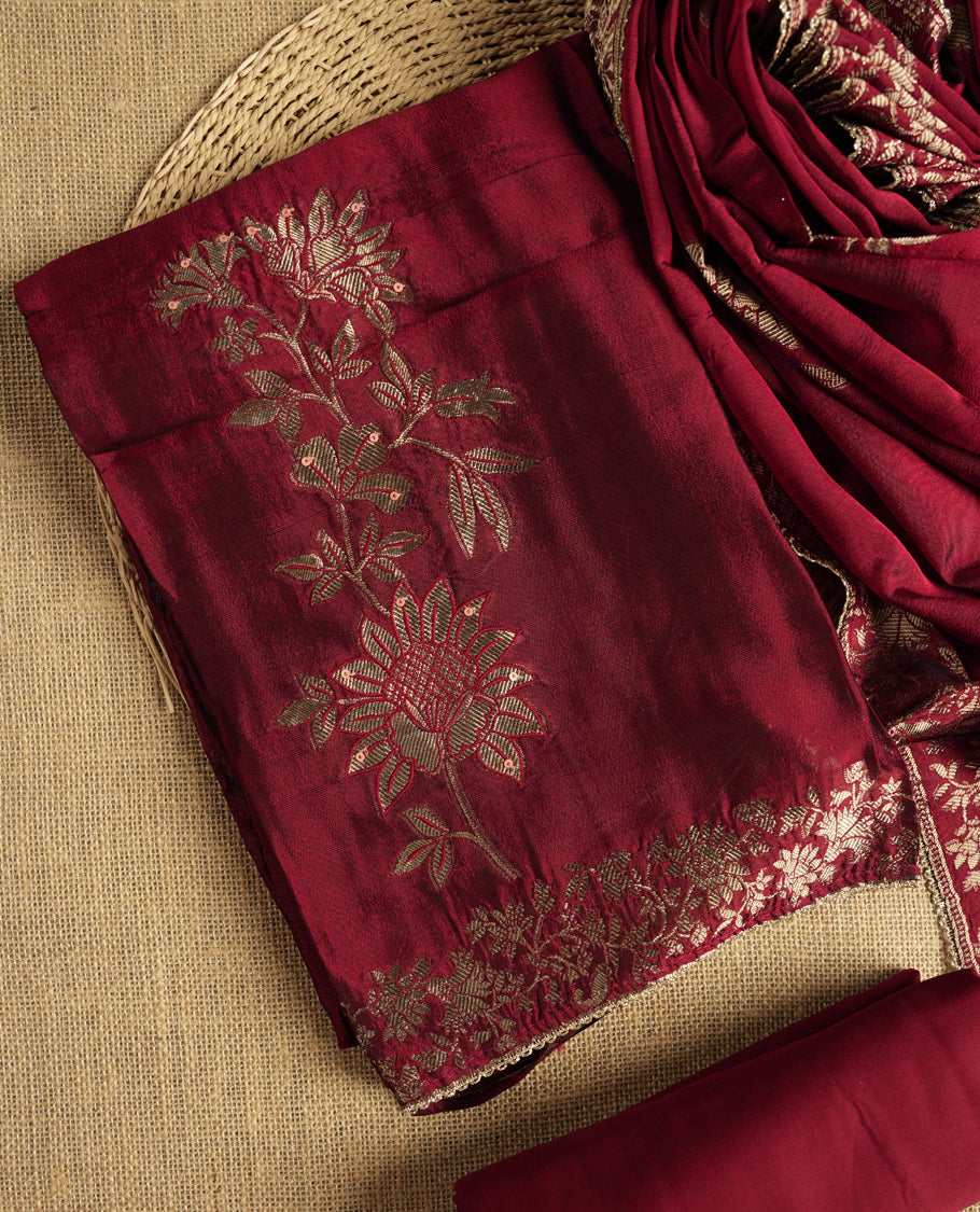 Elegant maroon colour suit material adorned with exquisite zari floral weaving, exuding regal charm & paired with a beautifully bordered dupatta and a matching plain bottom.
