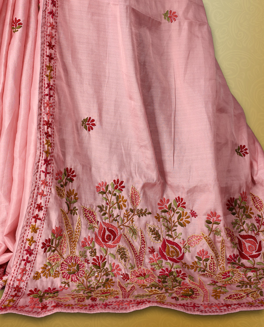 Pink colour pure tussar saree adorned with delicate multicolour floral embroidery along the border and scattered motifs across the body, paired with a matching blouse.