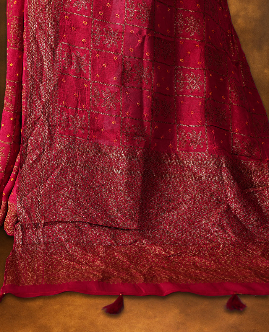Reddish pink Banarasi Bandhani saree featuring Bandhani dots in checkered zari motifs, a beautifully woven zari border, and a grand pallu with tassels. A graceful pick for festive and wedding wear.