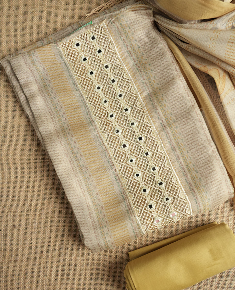 Pastel yellow and beige colour suit material with delicate woven mirror work patterns and subtle zari detailing & Includes a soft dupatta with a floral touch and plain matching bottom.