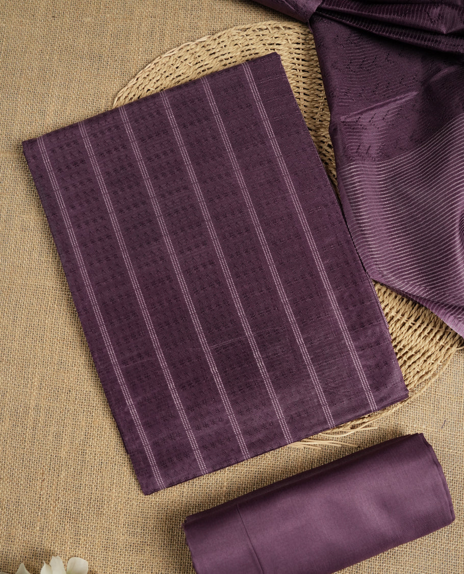 Dark lavender tussar suit material featuring a subtle self woven pattern and vertical lines on the body, paired with a lightweight matching dupatta with tassel edges and a plain bottom piece.