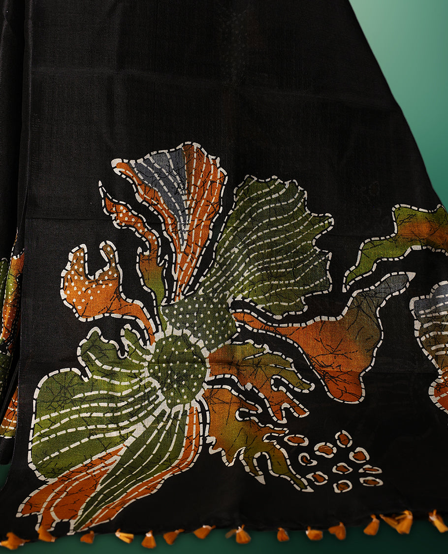 Black colour semi tussar saree adorned with multi colour bold floral motifs across the body, designed without a border for a contemporary touch, and paired with a matching blouse