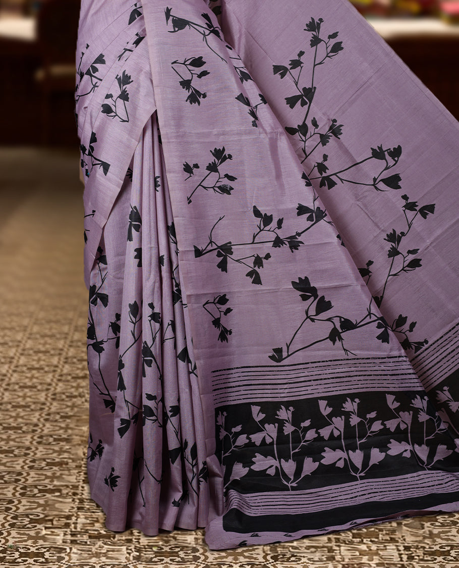 Pastel Lavender colour Semi tussar silk saree adorned with black floral prints on the body and an elegant pallu & Comes with a matching blouse piece for a classy look.