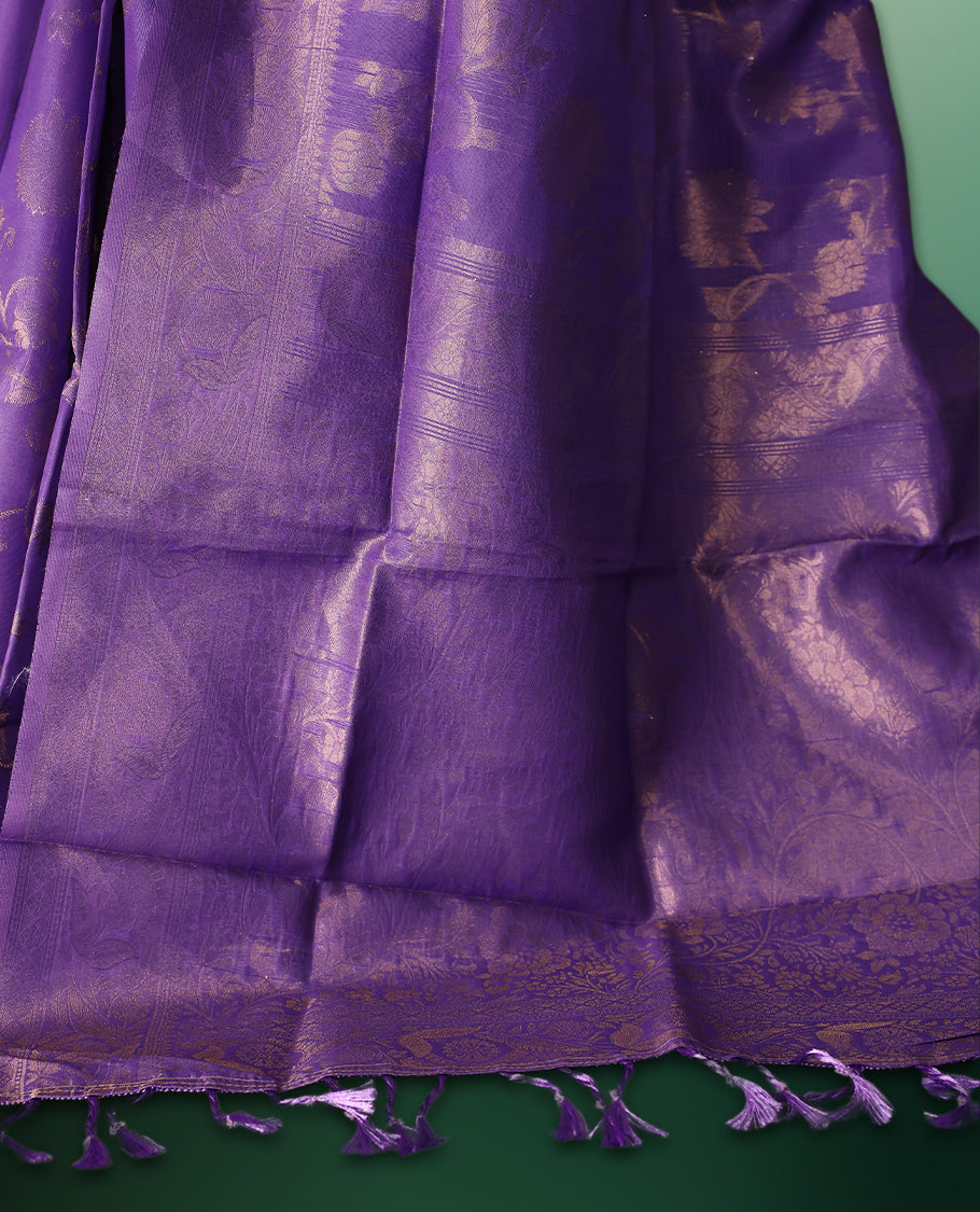 Lavender colour saree featuring subtle woven floral motifs with a lustrous finish, complemented by delicate tassels on the pallu, and paired with a matching blouse