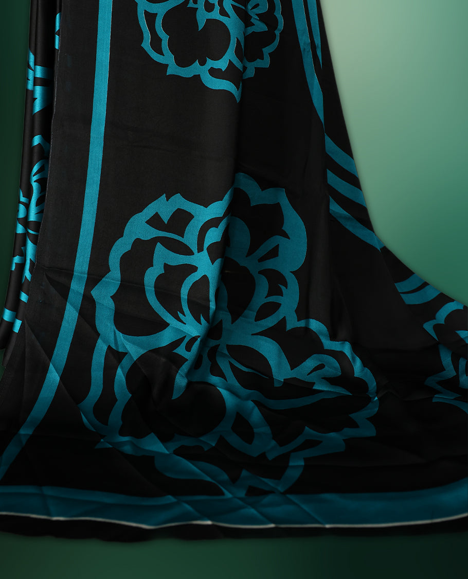 Black colour saree adorned with bold Light Blue floral motifs and matching border accents, paired with a coordinating blouse