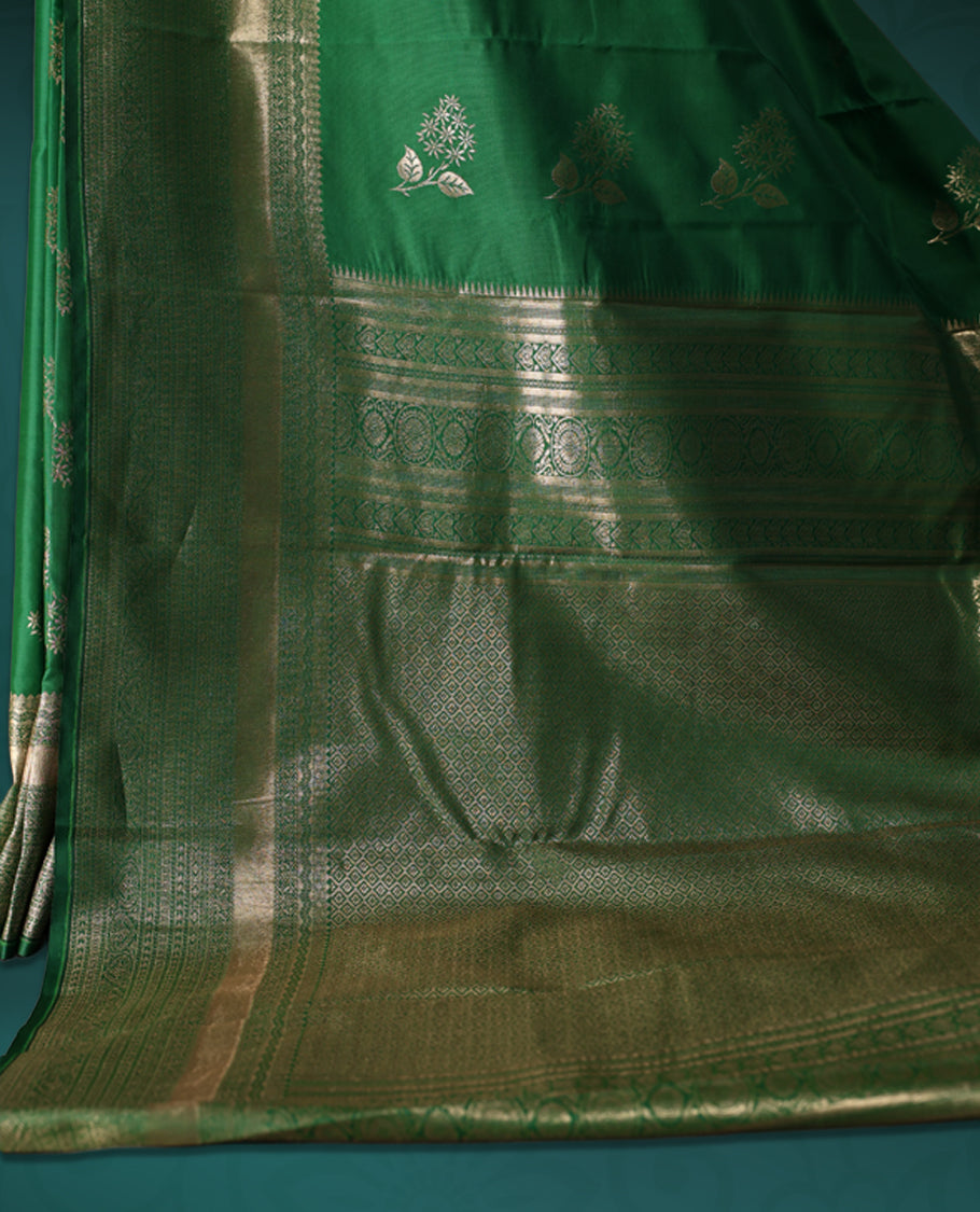 Green colour semi silk saree featuring golden zari floral motifs all over the body, complemented by a rich self colour woven border, with matching blouse.