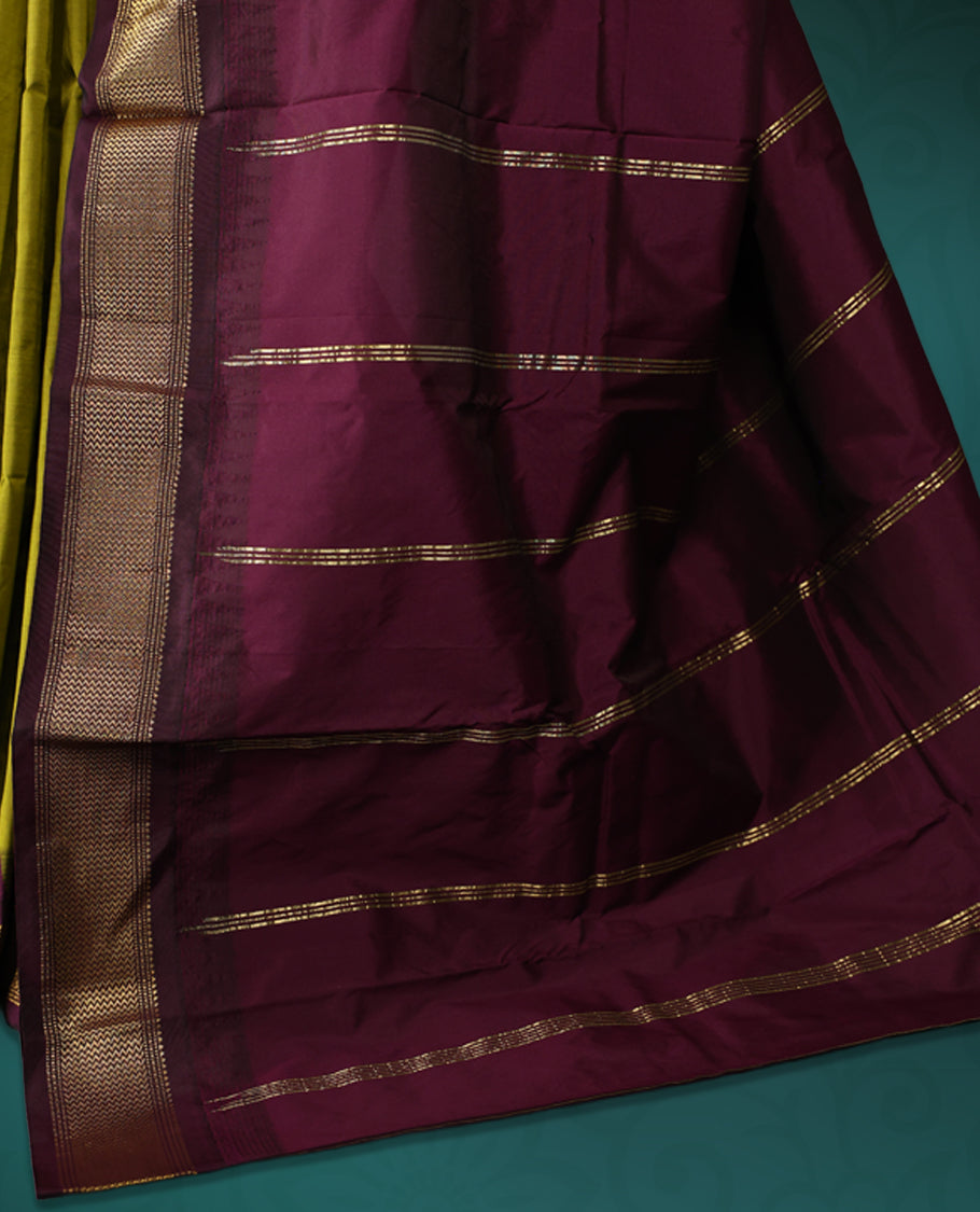 Olive green semi silk saree with plain body, vibrant deep purple pallu and matching purple border adorned with golden zari, accented with temple motifs along the edges, Paired with a matching blouse, perfect for festive occasions.