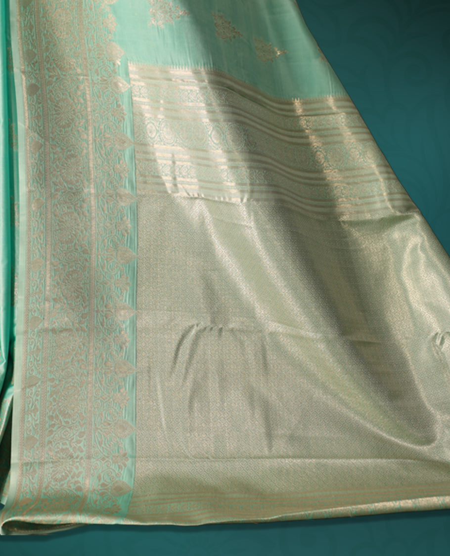Sea green colour semi silk saree featuring delicate golden zari floral motifs across the body, complemented by a rich self colour woven border and pallu, paired with a matching blouse.