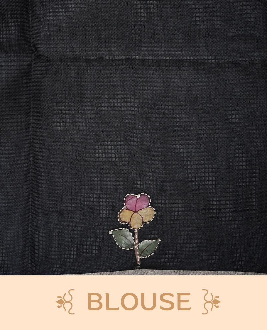 Black colour semi tusser silk saree showcasing delicate embroidered floral motifs throughout the body, finished with soft contrast detailing on the border and complemented by a matching embroidered blouse.