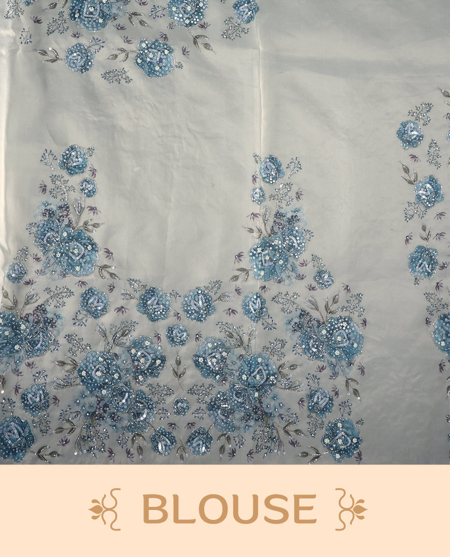 White colour pure organza saree featuring blue Colour floral prints with intricate bead and sequin work across the body, adorned with a matching embellished border, complemented by a worked pallu and paired with a heavily worked matching blouse.