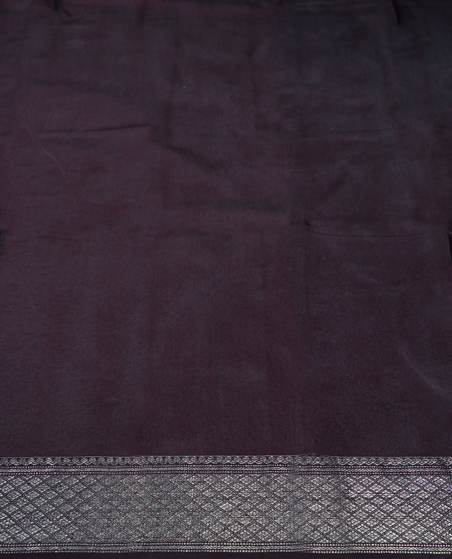Wine colour silk cotton saree adorned with a shimmering silver zari border and intricate woven designs, blending elegance with tradition, Paired with a matching blouse, its perfect for festive and special occasions.