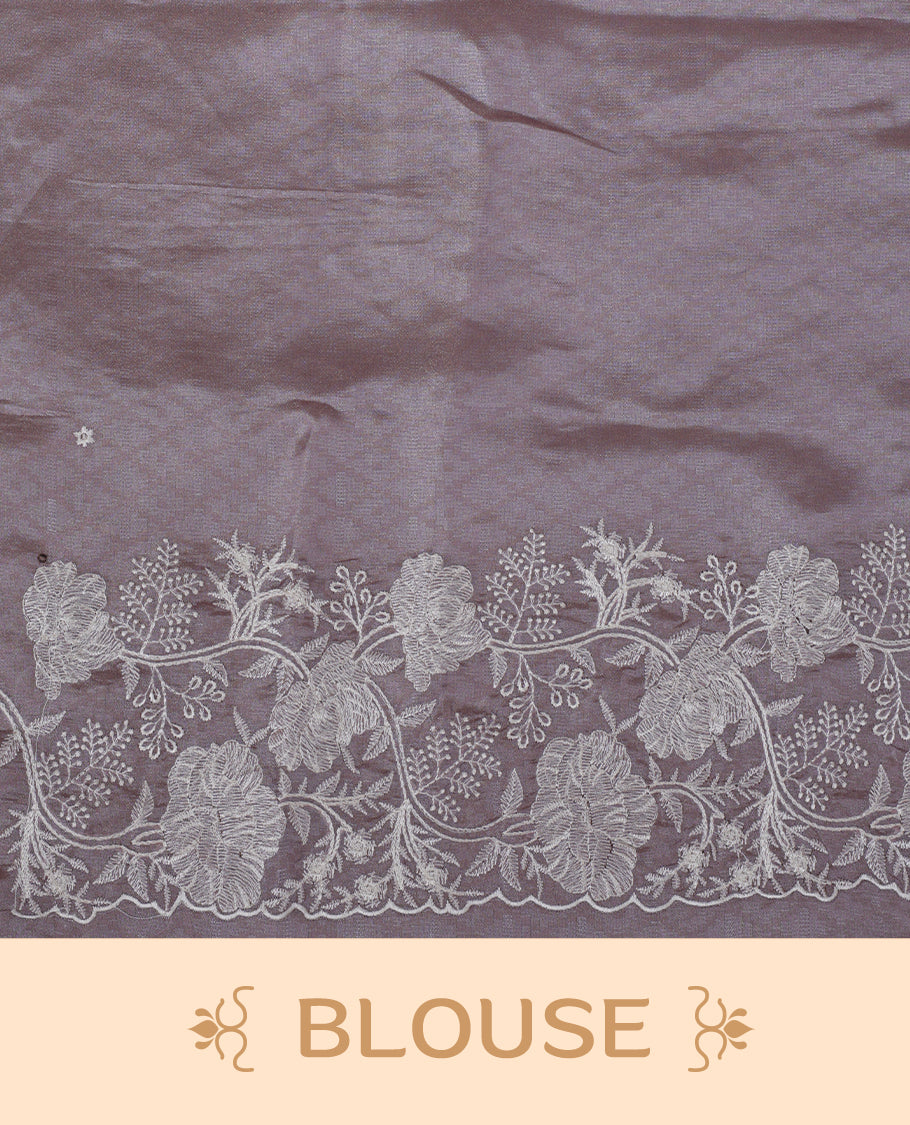 Lavender colour organza designer saree featuring a subtle self patterned body and an intricately scalloped floral thread embroidered border all around, complemented by a coordinating embroidered pallu and paired with a matching blouse.