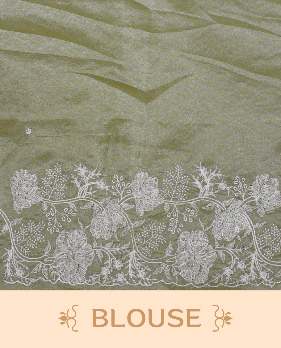 Pastel olive colour organza designer saree featuring a subtle self patterned body and an intricately scalloped floral thread embroidered border all around, complemented by a coordinating embroidered pallu and paired with a matching blouse.