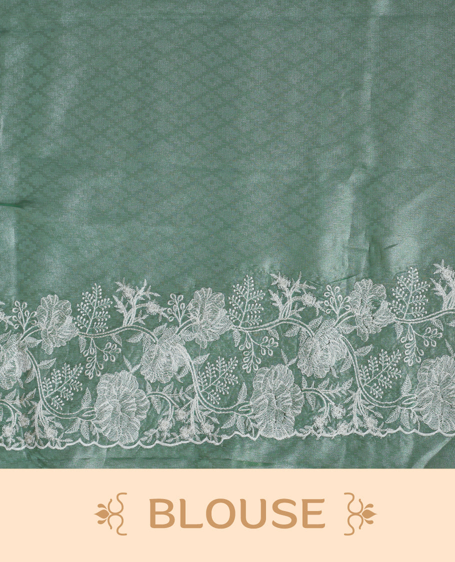 Light Green colour organza designer saree featuring a subtle self patterned body and an intricately scalloped floral thread embroidered border all around, complemented by a coordinating embroidered pallu and paired with a matching blouse.