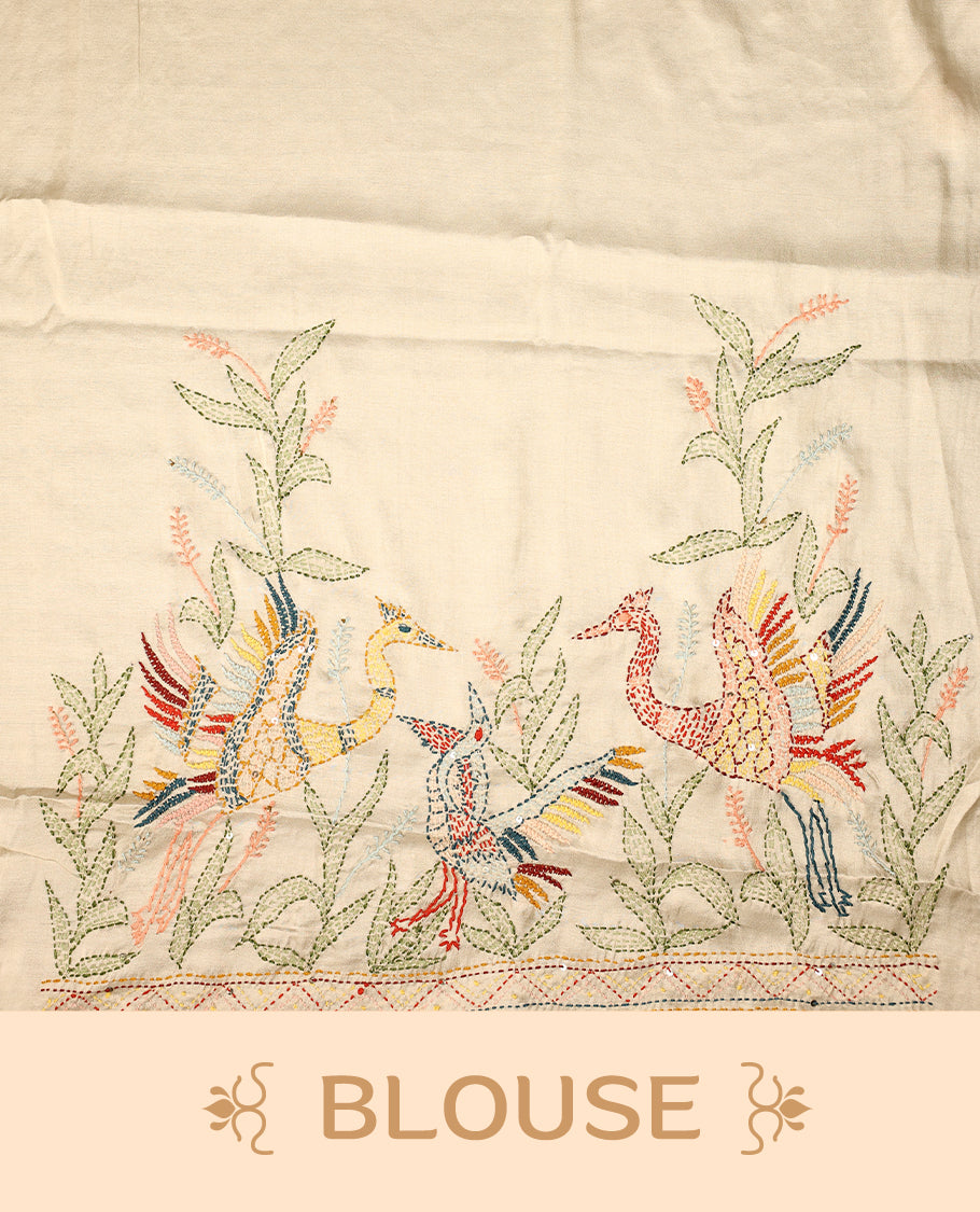 Cream colour pure tussar saree adorned with delicate Peach and green floral embroidery along the border and scattered motifs across the body, paired with a matching blouse.