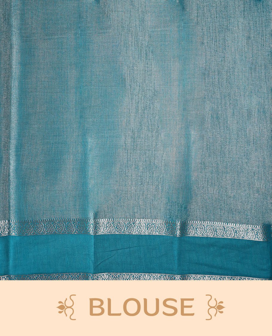 Steel grey saree with a rich sheen, paired with a contrasting turquoise blue border and pallu featuring delicate silver zari work, finished with tassels at the edge. Comes with a matching blouse piece.