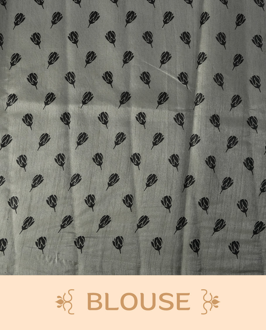 Grey colour saree with black floral prints all over the body, complemented by a contrasting black pallu adorned with bold floral designs and striped detailing & Paired with a matching blouse for a complete look.