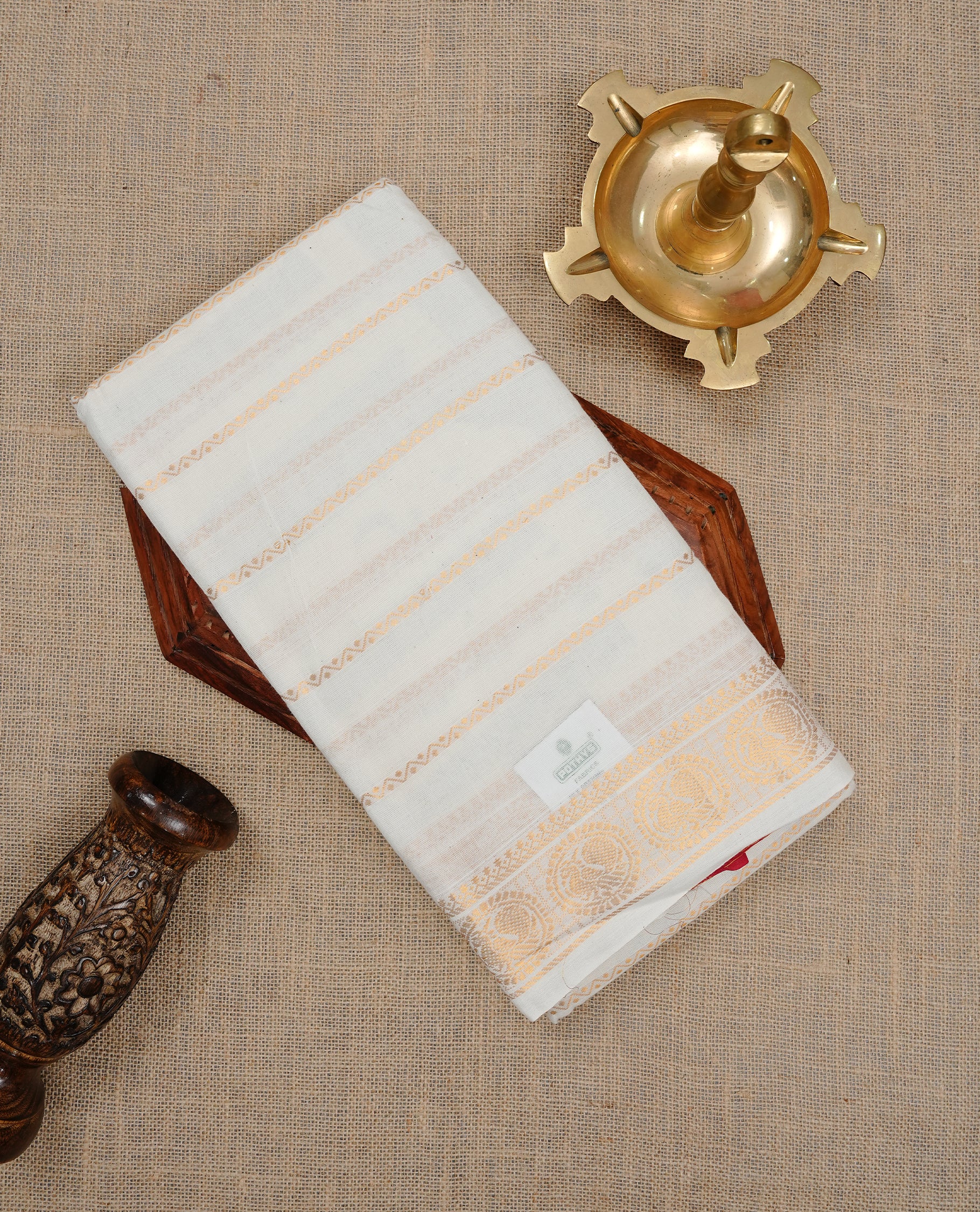 Off white colour Sungudi cotton saree featuring Gold zari Zigzag stripes on body, Gold zari Peacock chakram design on Self colour border, paired with matching blouse piece.