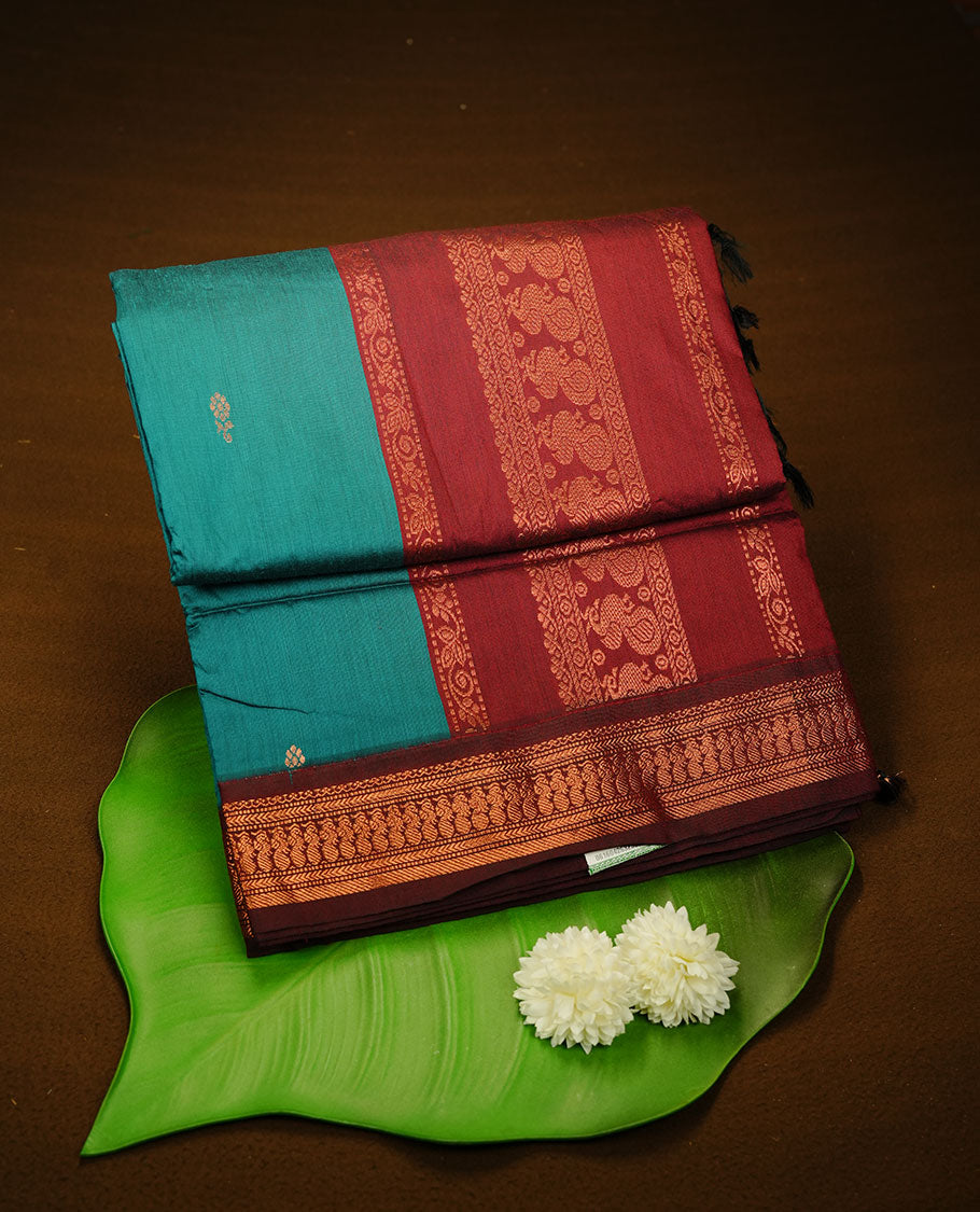 Teal colour kalyani cotton saree featuring antique zari motifs on body, complemented by Maroon colour with Antique zari border, paired with matching blouse piece.