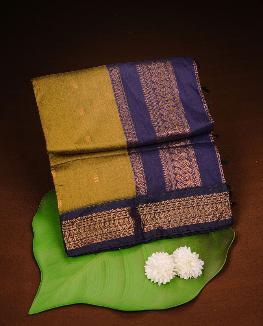 Olive colour kalyani cotton saree featuring antique zari motifs on body, complemented by Dark blue colour with Antique zari border, paired with matching blouse piece.